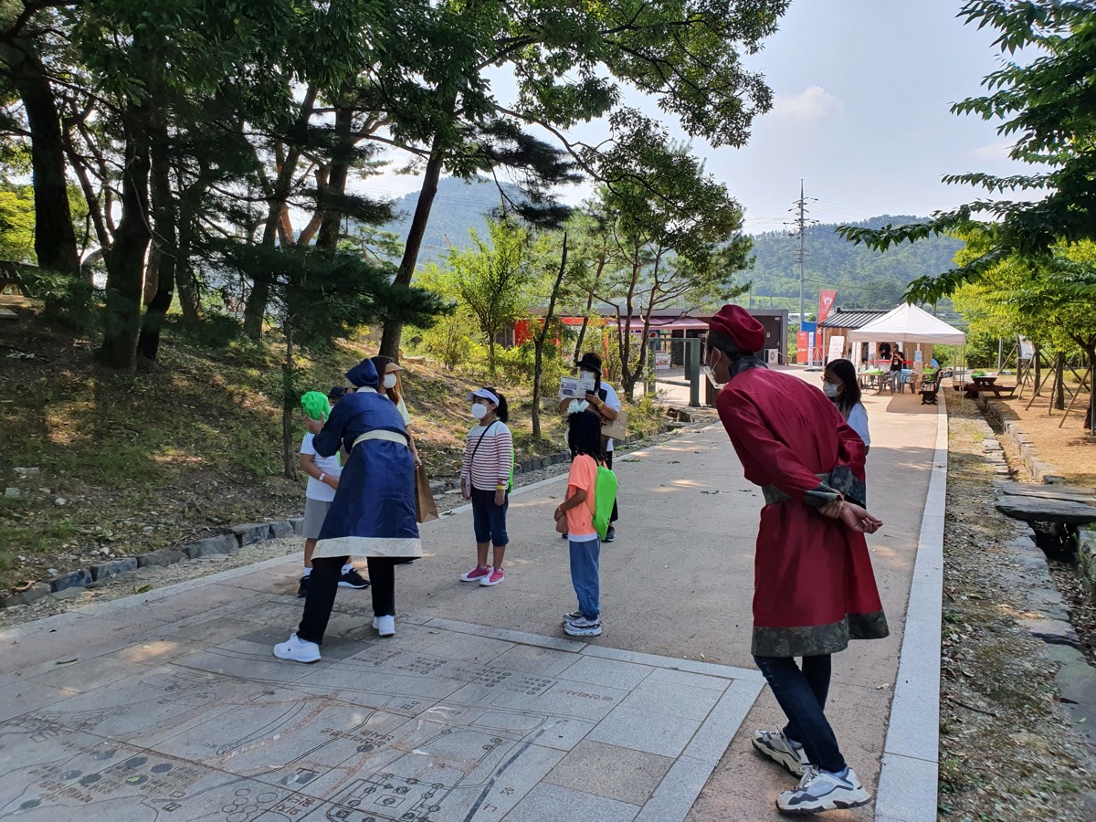 야외에서 안내자와 이야기를 나누는 어린이들